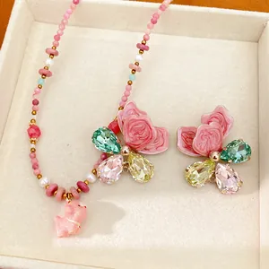 Close-up of pink ceramic beaded necklace with dog charm and crystal butterfly detail