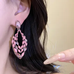 Detail view of pink bohemian hollow drop earrings with rhinestones on model's ear.