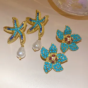 Detailed close-up of gold-tone starfish earrings with pearls and blue floral studs.