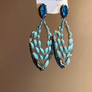 Close-up of bohemian teardrop hollow dangle earrings decorated with blue rhinestones