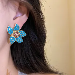 Macro view of elegant gold starfish earrings featuring turquoise beads and red rhinestones.