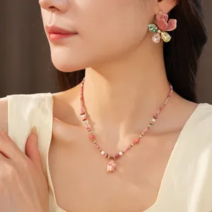 Close-up of pink ceramic beaded necklace with dog pendant and floral earrings on model