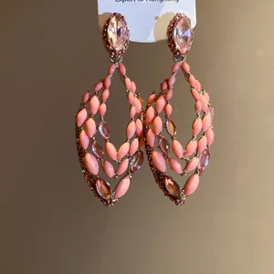 Detailed macro shot of bohemian openwork earrings with pink crystals and peach beads