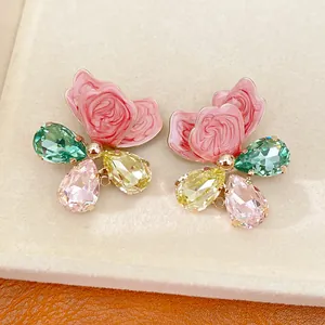 Macro detail of butterfly earrings with pink enamel petals and colorful pear-cut crystals.
