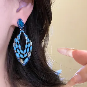Detailed macro view of Bohemian teardrop earrings with blue resin and sparkling crystals