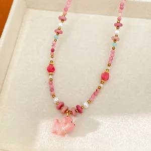 Macro view of a pink ceramic bead necklace featuring a cute puppy charm and pearls