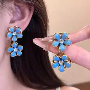 Detail of vintage light blue enamel flower earrings with sparkling rhinestone centers.