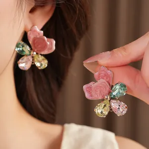 Detailed macro view of elegant butterfly earrings with pink petals and colorful crystals