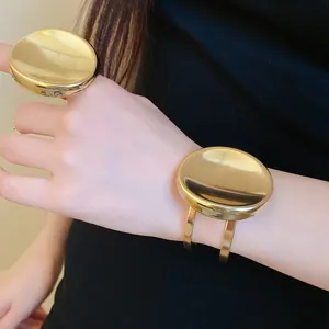 Gros plan d'un ensemble bague et bracelet ovales en métal doré poli sur le poignet