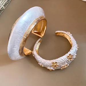 Elegant textured white and gold open cuff bracelet set with floral accents