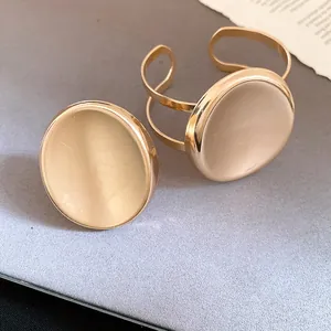 Ensemble élégant bracelet jonc et bague en métal doré ovale sur surface texturée.