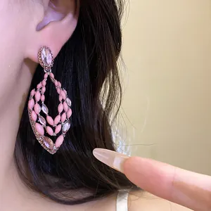 Close-up of pink teardrop hollow earrings featuring a Bohemian resort style design