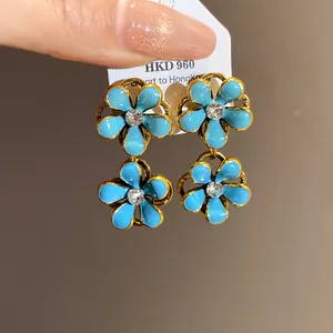 Detailed close-up of vintage blue enamel flower earrings featuring a sparkling central rhinestone.