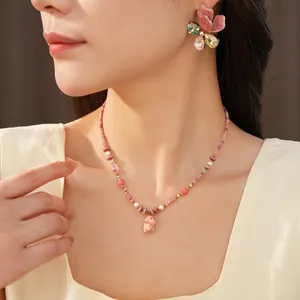 Detail of pink ceramic beaded necklace with dog pendant and butterfly earrings
