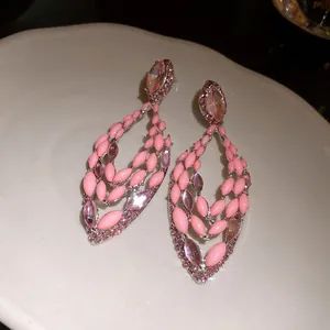Close-up of elegant pink crystal drop earrings with hollow marquise-shaped details.