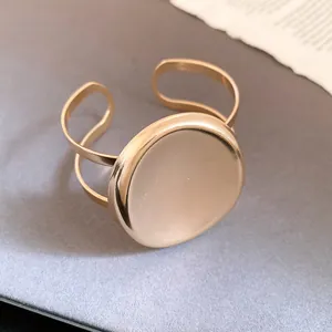 Détail d'un bracelet jonc doré minimaliste avec une grande plaque ronde polie et brillante
