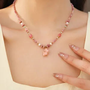 Detailed macro shot of a pink ceramic beaded necklace featuring a cute puppy pearl pendant