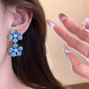 Detailed view of blue enamel flower dangle earrings with sparkling rhinestones.