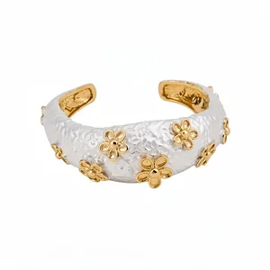 Elegant textured white metal open cuff bracelet featuring small golden flower appliqués