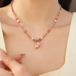 Detailed macro view of a pink ceramic puppy pendant necklace with beads and pearls