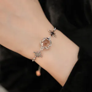 Macro detail of a silver zircon star bracelet with a central round glass bead on a wrist.