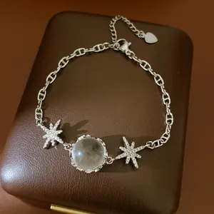Detailed close-up of a silver-toned star and moonstone bracelet on a brown leather jewelry box