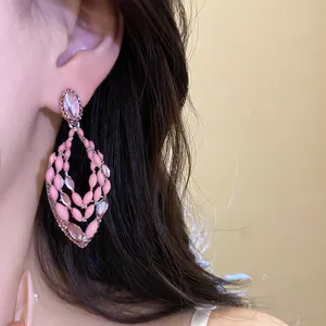 Close-up of pink enamel teardrop dangle earrings with crystals worn by model.