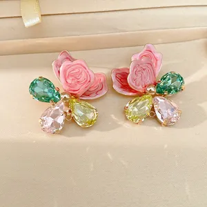 Close-up of floral jewelry charms with pink enamel petals and multi-color teardrop crystals