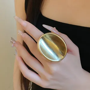 Gros plan détaillé d'une bague ouverte ovale métallique dorée minimaliste portée au doigt
