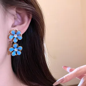 Close-up of vintage blue enamel flower earrings with diamond centers shown worn on ear.