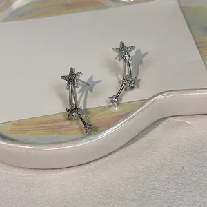 Detail showing elegant silver star earrings with sparkling zircon shooting star design