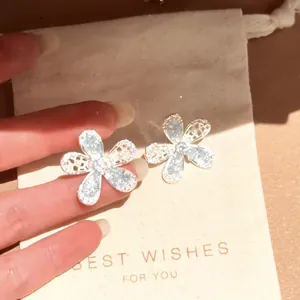 Close-up of elegant floral stud earrings with shimmering silver-tone flower petals.