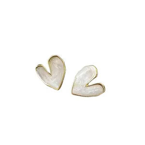 Minimalist gold-plated heart stud earrings with white swirled enamel finish and silver needles