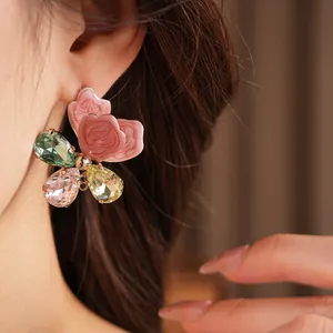 Close-up detail of a large flower-shaped earring with pink enamel and crystals