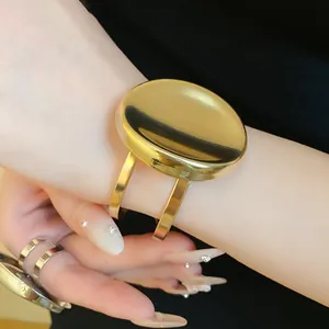 Gros plan sur un bracelet manchette ovale en métal doré et une bague assortie sur la main