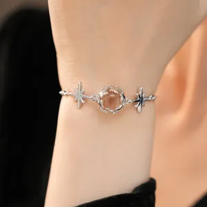 Close-up of a minimalist star-themed silver bracelet with a central crystal ball on wrist.