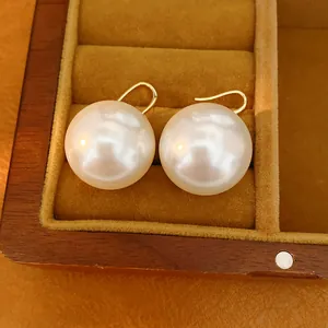 Macro detail showing lustrous large white pearl earrings resting in a wooden jewelry box
