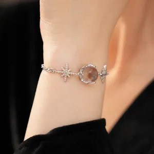 Celestial silver bracelet with starburst charms and translucent glass bead on wrist.
