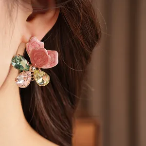 Detailed view of a pink floral earring with multi-colored teardrop crystals on model