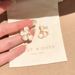 Close-up detail of elegant shimmering flower-shaped earrings displayed on a gift card pouch.