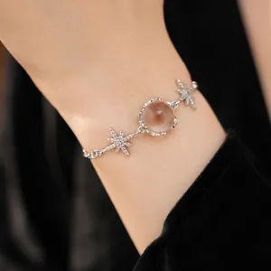 Close-up of a silver starburst bracelet with zircon accents and a clear glass bead