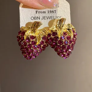 Boucles d'oreilles fraises élégantes avec strass violets et tige dorée sur carte