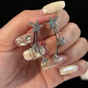 Close-up detail of elegant silver shooting star earrings with sparkling white zircon stones.