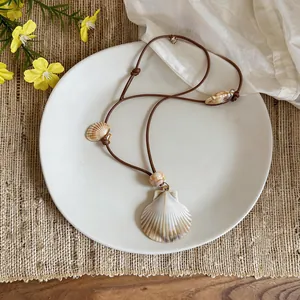 Detail view of Bohemian shell necklace on white plate with summer beach holiday vibes