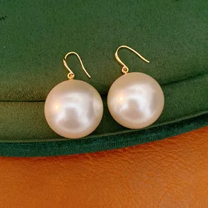 Detail view of 18k gold plated large pearl drop earrings on velvet background