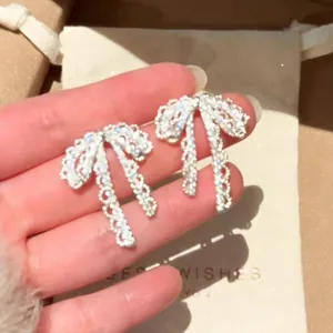 Close-up detail of sparkling silver-tone bow earrings with inlaid crystal rhinestones.