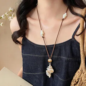 Close-up of bohemian style conch shell pendant necklace worn on brown adjustable cord