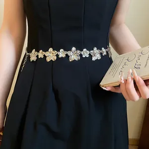 Primo piano squisito di una catena in vita in metallo a fiori argento su un abito nero classico