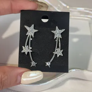 Close-up detail of silver-tone shooting star earrings with shimmering zircon crystal inlays