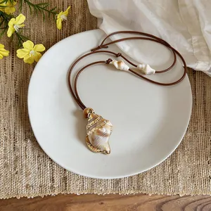 Detailed view of a Bohemian conch shell pendant necklace with a brown waxed cord.